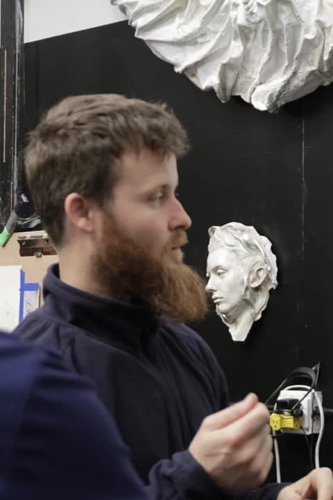 Matthew Riggs in the studio, beside a plaster cast with student drawings of it pinned on the wall.