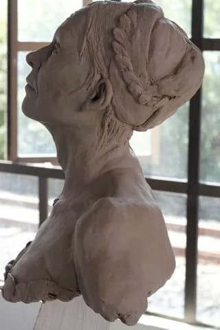 The same clay bust seen in profile against a studio window.