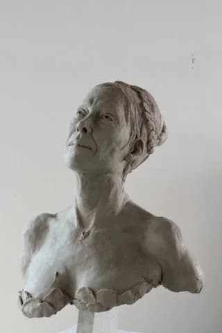 Clay bust of a woman with her head turned and raised, hair bound up.