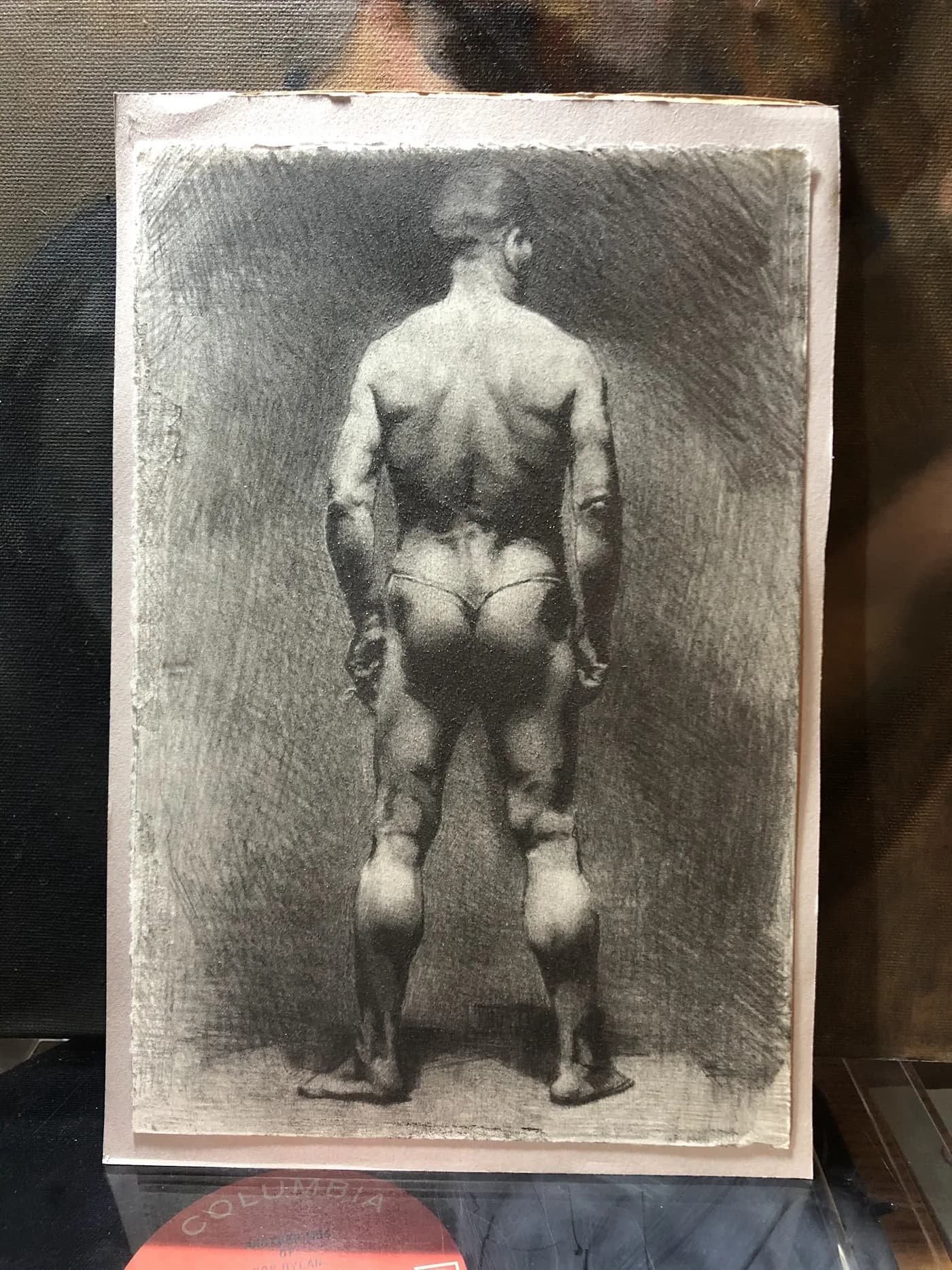 Charcoal study of a standing figure seen from behind, taped to the drawing board.