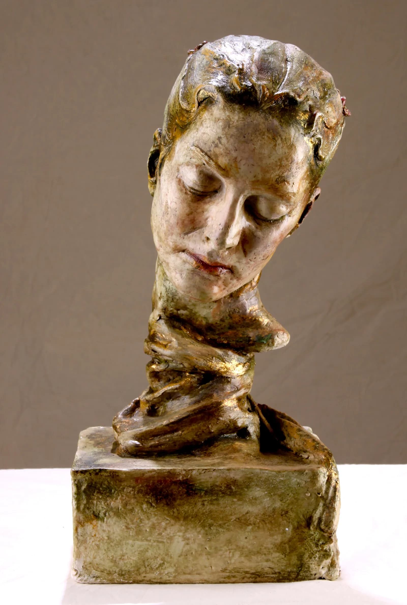 Gilded bronze bust of a woman on a plinth, warm light across the shoulders.
